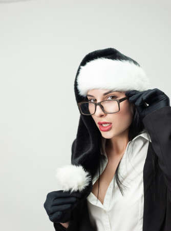 portrait of a woman in a black business suit with glasses and a black Santa hatの写真素材