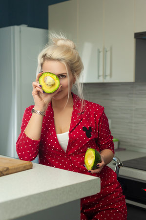 blonde vegan holding avocado in the kitchen