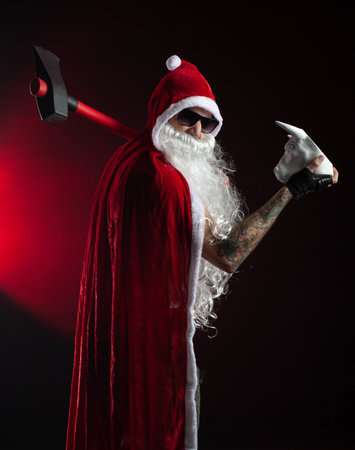 a man in a red Santa Claus Cape with an axe and a metal bull figurine symbol of the new year 2021の写真素材
