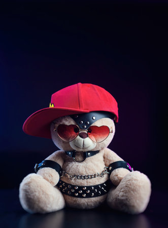 toy bear with glasses in the form of a heart and a red baseball cap on a leather belt accessory for BDSM games gift for Valentines dayの写真素材