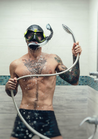 a man wearing a scuba mask in the shower is doused with waterの写真素材