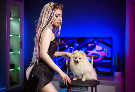 portrait of a sexy woman with dreadlocks in a corset with a cute pomeranian dogの写真素材