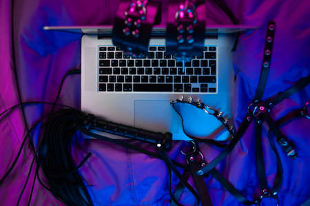 A set of BDSM toys for sex on a laptop on a bright neon backgroundの写真素材