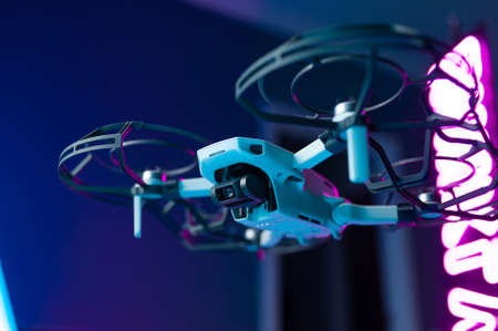 The smallest drone. unmanned aerial vehicle with blade protection and camera in flight in neon light . Russiaのeditorial素材