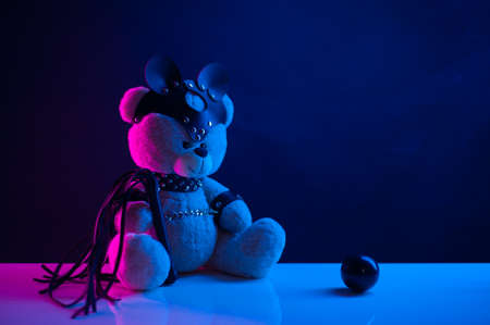 toy bear dressed in leather belts harness accessory for bdsm games on a dark backgroundの写真素材