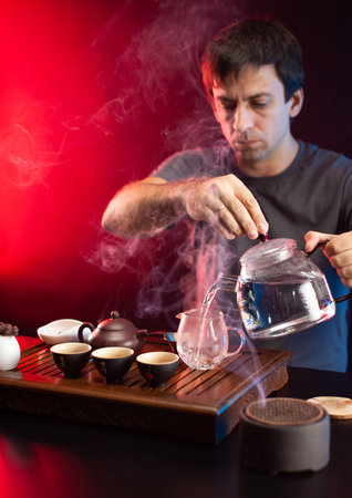 a man makes tea at a tea table with appliances according to the traditional Chinese traditionの写真素材
