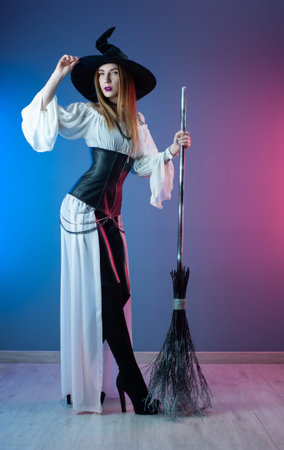 slender girl in a witch costume for Halloween with a broom