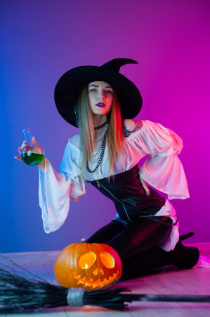 a girl in a witch costume for Halloween with a broom and a pumpkin in neon light