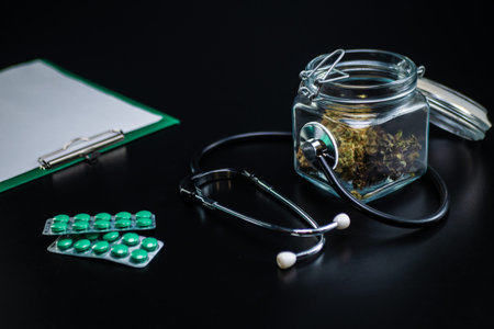 Dry medical cannabis in a jar with a stethoscope on a black background