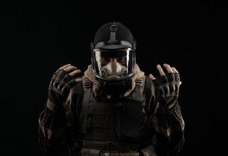 a man in a military uniform and a gas mask holds with an angry expression of emotions on a black...