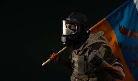 a male soldier in military uniform in a bloody gas mask holds a bloodstained flag of Russia on a black backgroundの写真素材