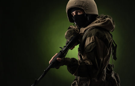a Russian soldier in a helmet in military clothes with a  assault rifle on a dark background in the studioの写真素材