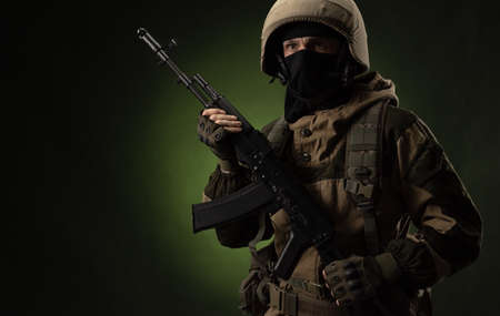 a Russian soldier in a helmet in military clothes with a   assault rifle on a dark background in the studioの写真素材