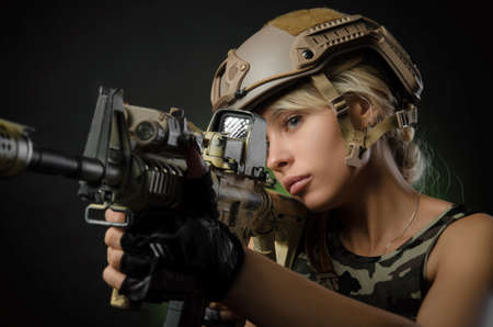 a girl soldier armed with an automatic rifle takes aimの写真素材