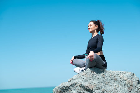 sporty girl in sportswear on a rock by the sea