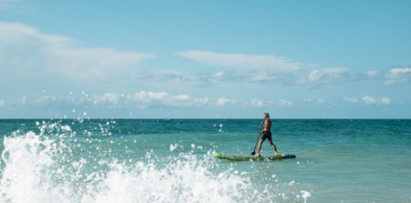 athletic wiry surfer guy swims with a paddle on a sapboard in the seaの写真素材