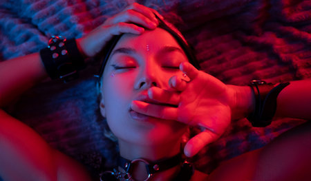 portrait of a sexy girl in a leather mask and bdsm accessories on a bed enjoying sex in orgasm with...
