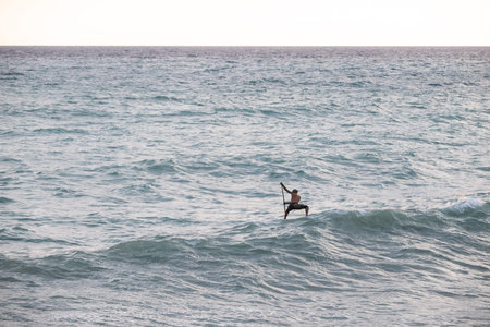 athletic wiry surfer guy swims with a paddle on a sup board in the sea Stand up paddleboarding