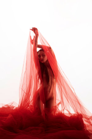 girl under a transparent red cloth on a white background dances and poses with a beautiful bodyの写真素材
