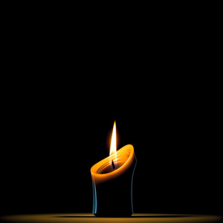 A burning candle on a black background with space for text.の素材