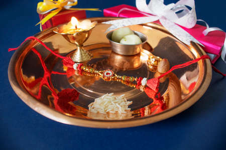 Indian festival: Raksha Bandhan background with an elegant Rakhi, Rice Grains and Kumkum Raksha bandhan with sweets gifts flowers and diyaの写真素材