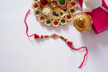 Indian festival: Raksha Bandhan background with an elegant Rakhi, Rice Grains and Kumkum Raksha bandhan with sweets gifts flowers and diyaの写真素材