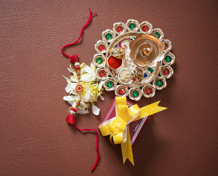 Indian festival: Raksha Bandhan background with an elegant Rakhi, Rice Grains and Kumkum Raksha bandhan with sweets gifts flowers and diyaの写真素材