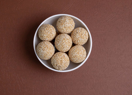 The indian sesame sweet or tilgul laddu, made up of jaggery and sesame seeds, indian sweet for Makar Sankranti festival, pile or stacked on black background, closeup showing texture, selective focusの写真素材