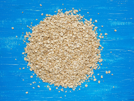 Heap of oat flakes in circle shape on bright blue background. shot from above