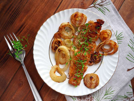 Grilled fish on white plate with onions and micro greensの写真素材