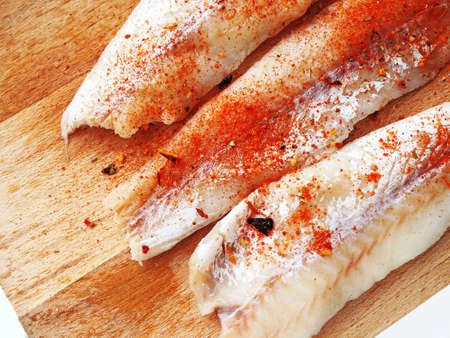 Fish fillet salted and pappered for cooking or grill on wooden backgroundの写真素材