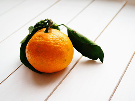 tangerine with leaves on white wooden background