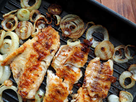 Fish fillet Grilled on a pan with onionsの写真素材