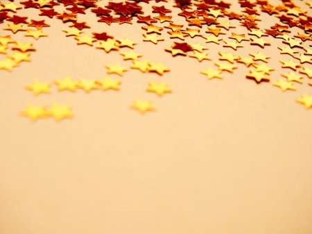 Golden stars glitter on yellow background. Festive holiday bright backdrop