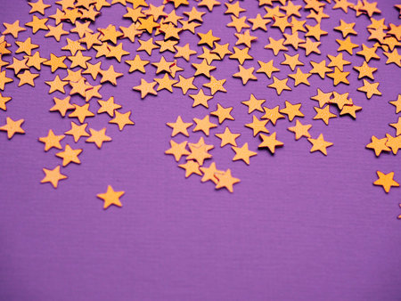 Golden stars glitter on lavender paper background. Festive holiday bright backdrop