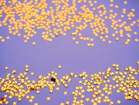 Golden stars glitter on lavender paper background. Festive holiday bright backdrop