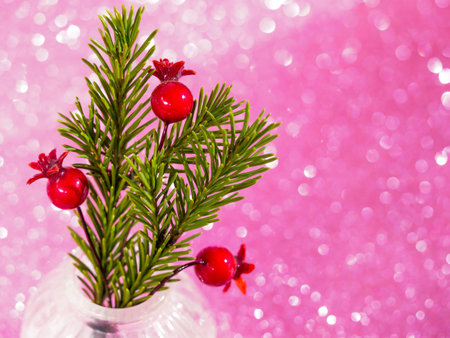 Christmas decor with fir and berries in a vase on pink bokeh background. Christmas time decorations...