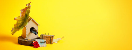 Wooden bird house with suitcase, map, pasport and ticket on a bright yellow background. Social media...