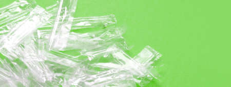 Pile of transparent plastic wrapping rubbish on a green background. Top view of many plastic wrappings for juice straws with copy space for text. Social media banner or header.の写真素材
