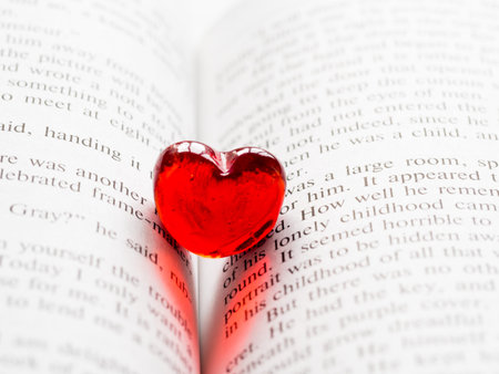 Red transparent glass heart lay in a book. Valentine's day concept. Beautiful romantic backdrop.