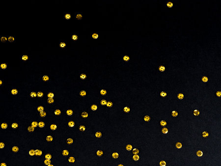 Golden paillette glitter on black background. Festive holiday bright backdrop