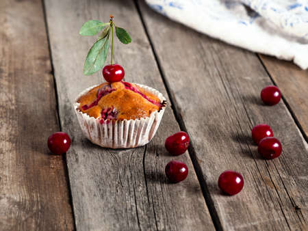 Bunch of freshly baked cherry muffins with fresh berries on a rustic wooden tableの写真素材