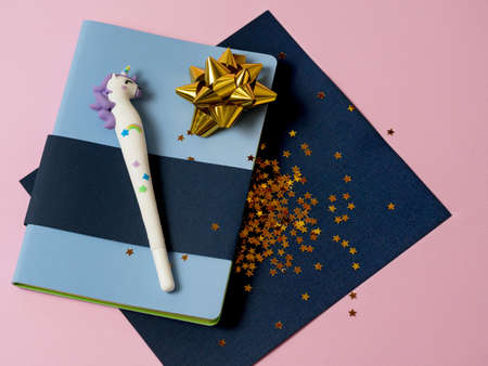 Blue notebook with with cute unicorn pen and gold bow and stars glitter on pink background. Girls note, magic diary with unicorn.の写真素材