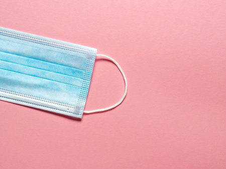 Medical protective mask on a pastel pink background. Individual, disposable surgical face mask....