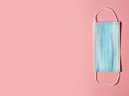 Medical protective mask on a pastel pink background. Individual, disposable surgical face mask. Quarantine healthcare, hygiene and coronavirus protection concept.の写真素材