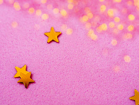 Gold star glitter confetti splashed on pink paper background. Festive twinkle glitter background.の写真素材