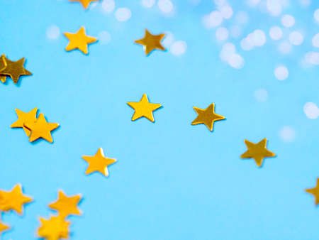Gold star glitter confetti splashed on blue paper background. Festive twinkle glitter background.の写真素材
