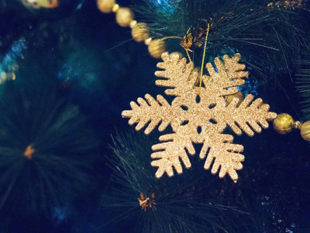 Golden snowflake decoration hanging from a decorated christmas tree. New year bauble closeup foto...