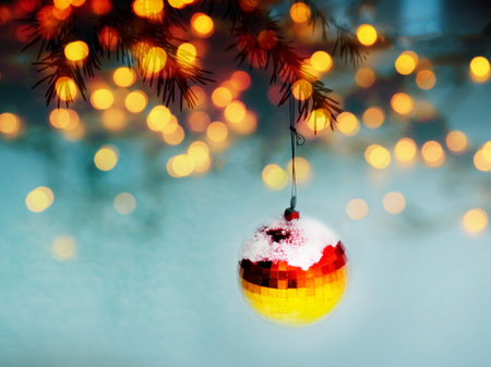 Red ball hanging from a decorated christmas tree. New year bauble closeup foto with bright bokeh....
