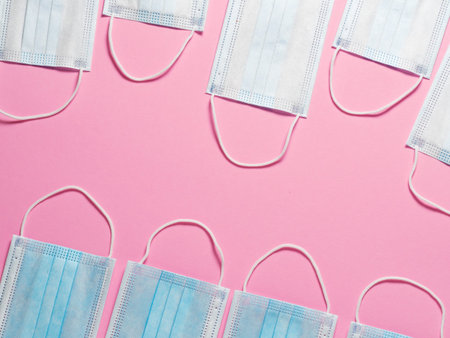 Medical protective masks on a pastel pink background. Individual, disposable surgical face mask flat...